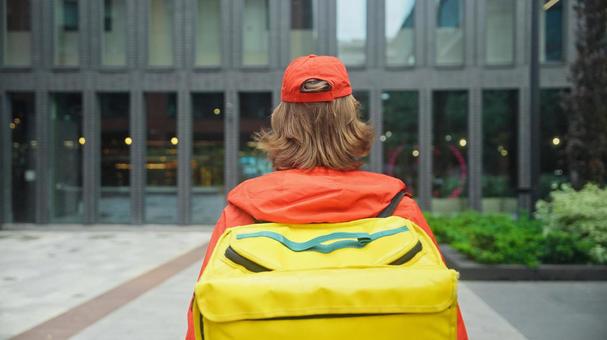 街なかにいるフードデリバリーの男性の後ろ姿 配達,フードデリバリー,デリバリーの写真素材