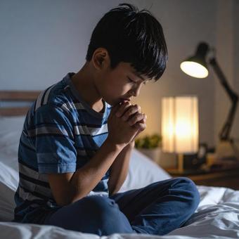 ベッドの上で祈る少年 ベッドの上で祈る少年の写真