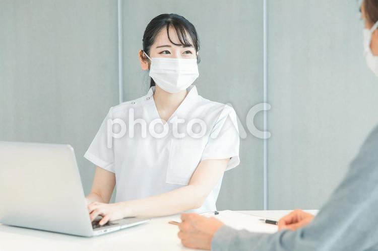 パソコンで受付する白衣の女性と患者（笑顔） 医療事務,医者,レセプトの写真素材