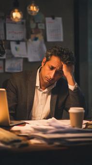 頭を抱え書類を読むインド人ビジネスマン 頭を抱え書類を読むインド人ビジネスマンの写真