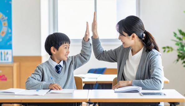 ハイタッチする塾講師と小学生の男の子 ハイタッチする塾講師と小学生の男の子の写真