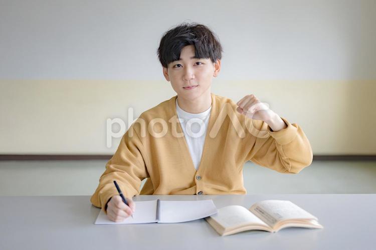 勉強しながらガッツポーズする私服の男性 受験,勉強,テスト勉強の写真素材