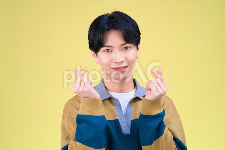 両手で指ハートをする笑顔の男性 男性,アイドル,笑顔の写真素材