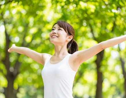 自然の中で手を広げて森林浴をする若い女性 自然の中で手を広げて森林浴をする若い女性の写真