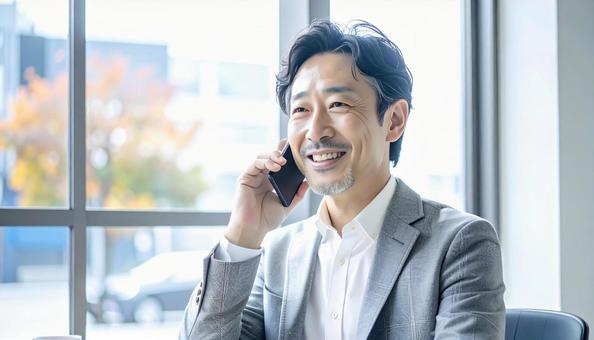 笑顔で電話する中年の写真