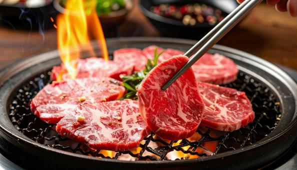 焼肉を鉄板で焼いて鉄箸ですくう 焼肉を鉄板で焼いて鉄箸ですくうの写真