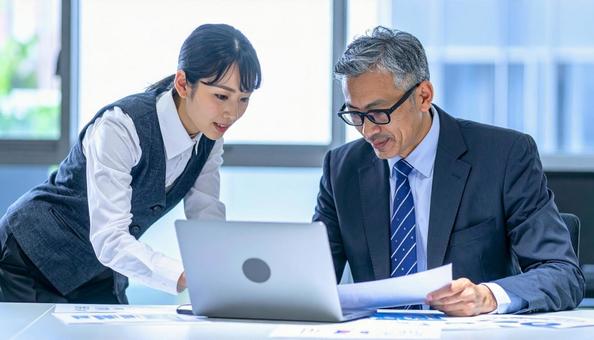 データを見ながら相談する上司と部下 データを見ながら相談する上司と部下の写真