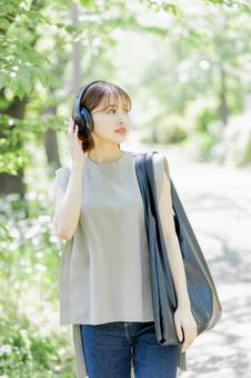 新緑の中ヘッドフォンで音楽を聴く若い女性 新緑の中ヘッドフォンで音楽を聴く若い女性 女性,外出,ヘッドフォンの写真素材