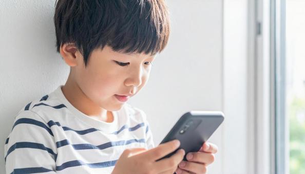 スマホを操作する小学生のこども スマホを操作する小学生のこどもの写真