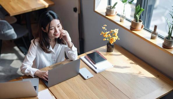 カフェで仕事をするフリーランス女性 カフェで仕事をするフリーランス女性の写真