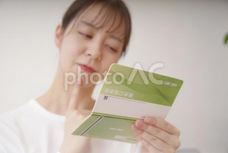 通帳を見て複雑な表情をする女性 女性,悩む,ショックの写真素材
