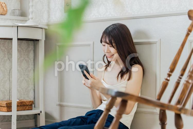部屋着でスマホを操作する笑顔の女性 女性,人物,スマホの写真素材