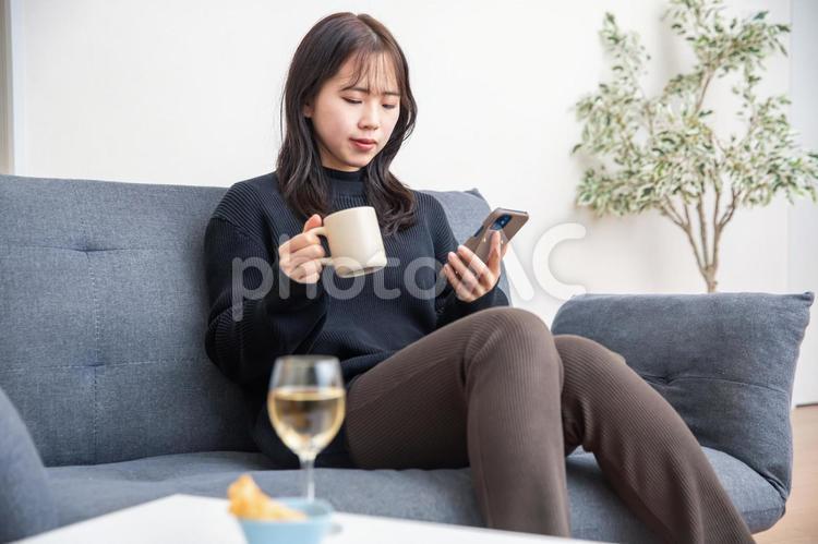 ソファーでスマホを見る女性　relax 風邪,体調不良,薬の写真素材