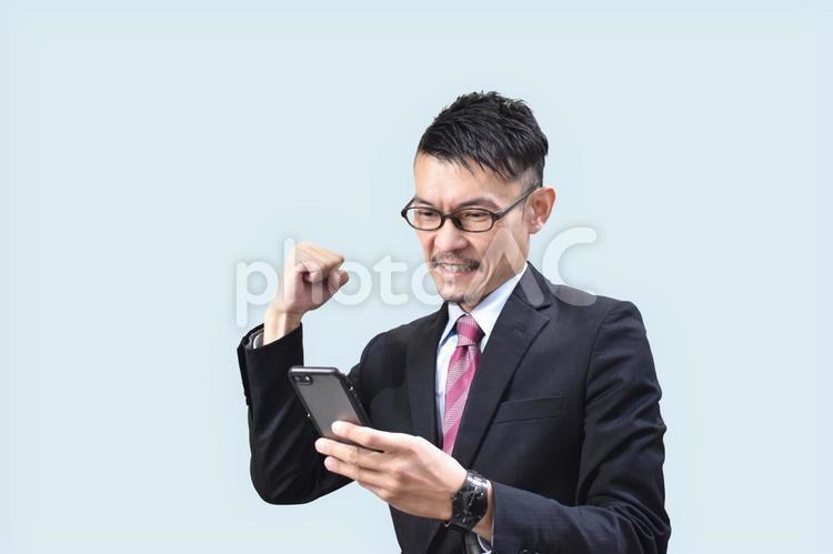 スマホを見てうれしそうなビジネスマン スマホ,ビジネスマン,男性の写真素材