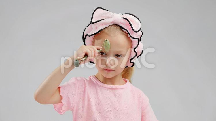 真顔でフェイスローラーでマッサージする女の子 女の子,フェイスローラー,マッサージの写真素材