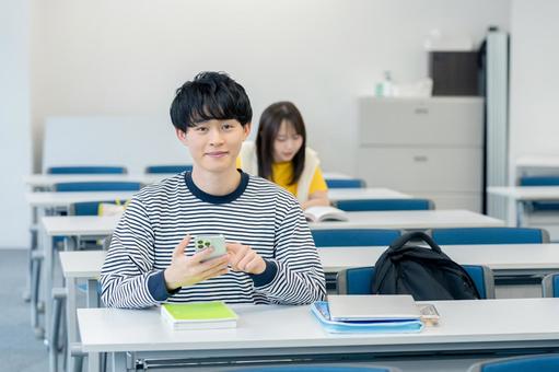 教室でスマホを見る大学生 スマホ,笑顔,大学生の写真素材