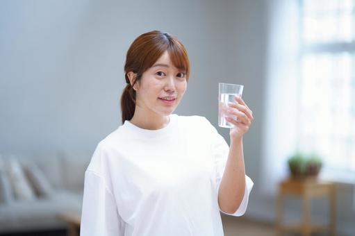 カメラ目線で水のコップを持つ女性 女性,水,飲み物の写真素材