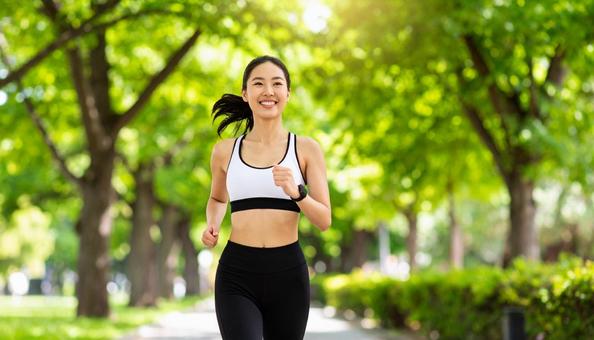 夏の公園でジョギングする若い日本人女性 夏の公園でジョギングする若い日本人女性の写真