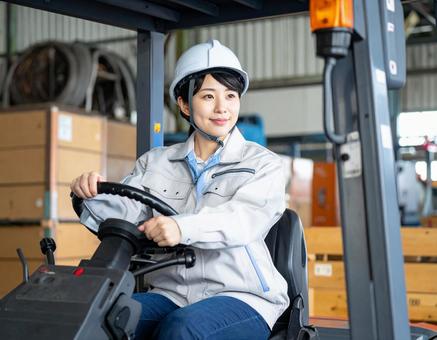 フォークリフトを運転する女性作業員 フォークリフトを運転する女性作業員の写真