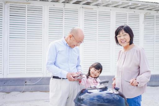 孫とバーベキューをする高齢の夫婦 バーベキュー,キャンプ,手を振るの写真素材