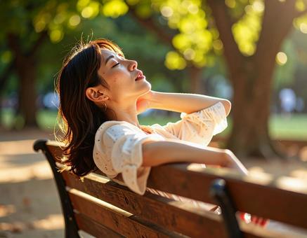 ベンチでリラックスする女性 ベンチでリラックスする女性の写真