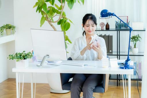 オフィスでスマホを持つビジネスウーマン スマホ,笑顔,ビジネスウーマンの写真素材