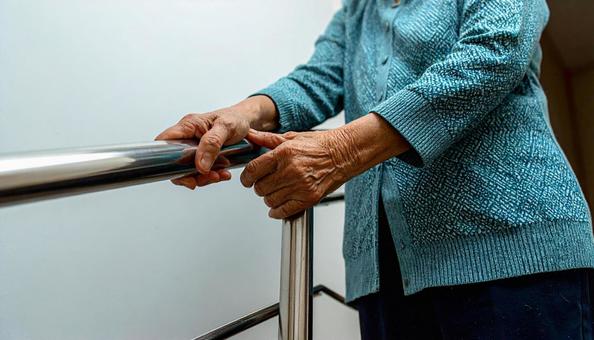 階段の手すりをつかむ老人の手 階段の手すりをつかむ老人の手の写真