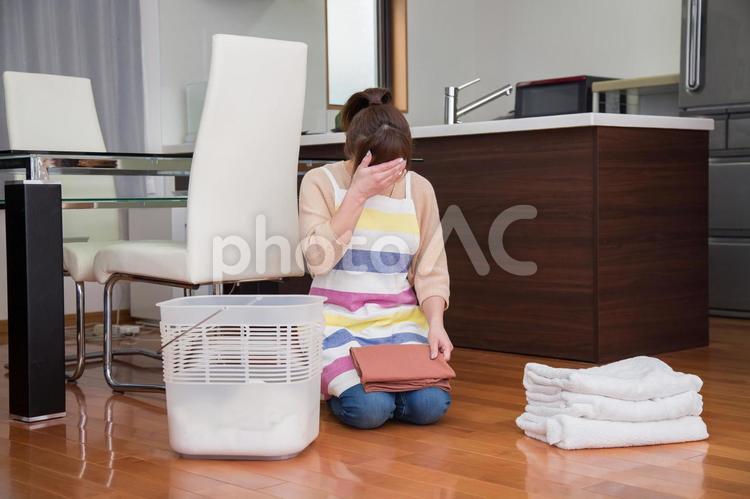 家事にストレスをかかえる女性 洗濯物,たたむ,泣くの写真素材