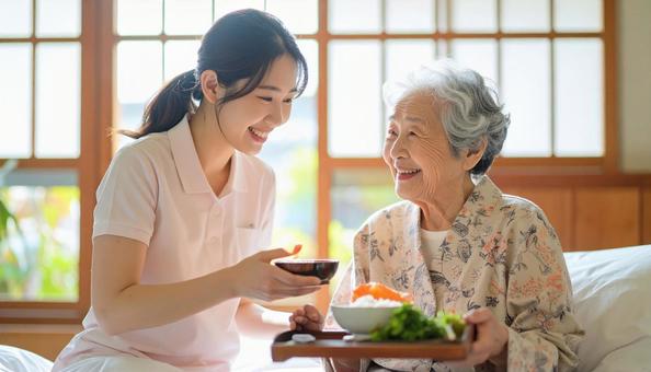 高齢女性と女性介護士の穏やかな食事風景 高齢女性と女性介護士の穏やかな食事風景の写真