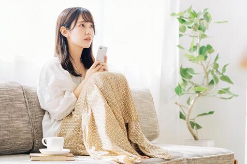 ソファに座ってスマホを見る女性 女性,スマホ,ソファの写真素材