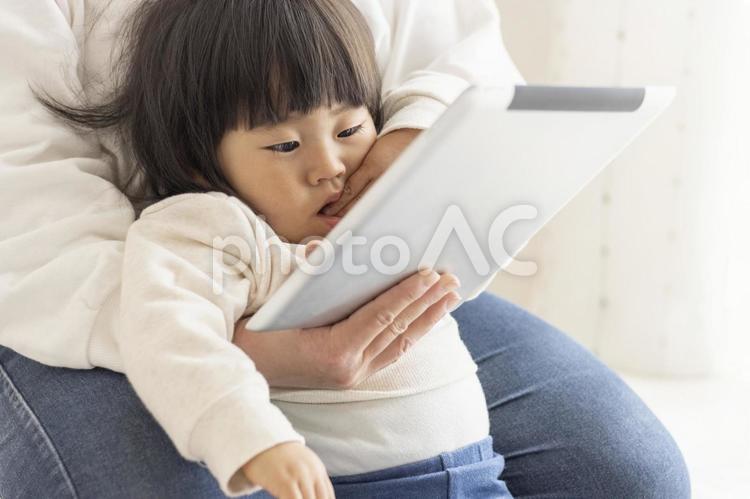 タブレット端末を見る赤ちゃん（1歳8か月、女の子、日本人）と、それを見せる母親の手（30代、日本人） タブレット,親子,母娘の写真素材