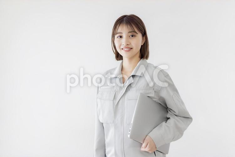ノートパソコンを持つ作業服の女性 女性,人物,日本人の写真素材