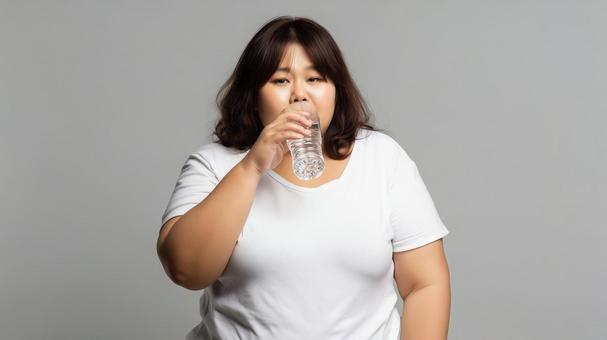 味気なさそうに水を飲むダイエット中の女性 味気なさそうに水を飲むダイエット中の女性の写真