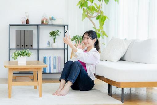 部屋でスマホを操作する若い女性 スマホ,笑顔,若い女性の写真素材