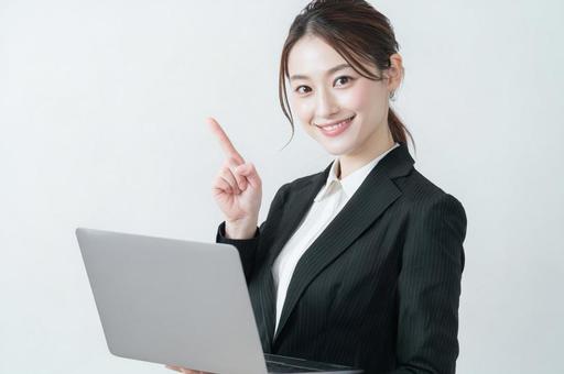 パソコンを持ち指をさす女性-1 パソコンを持ち指をさす女性-1の写真