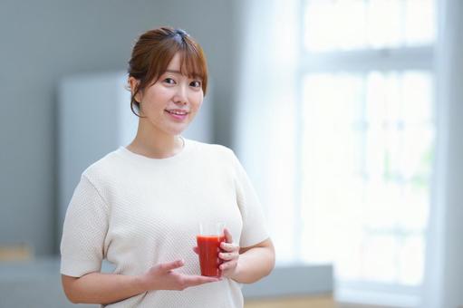 手を添えカメラ目線でコップを持つ女性 女性,トマトジュース,赤の写真素材