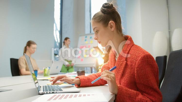 ノートパソコンを使っている女性と話し合う同僚 ビジネス,ビジネスマン,ビジネスウーマンの写真素材