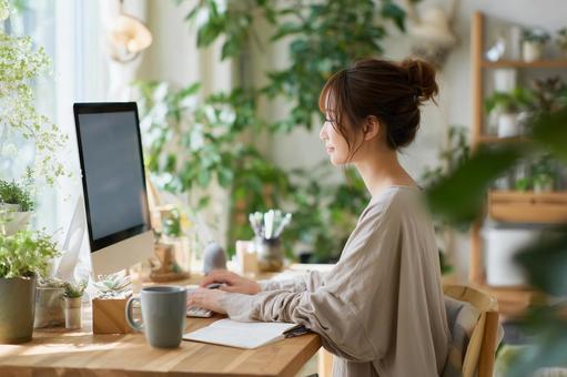 部屋でパソコン作業をする女性 部屋でパソコン作業をする女性の写真
