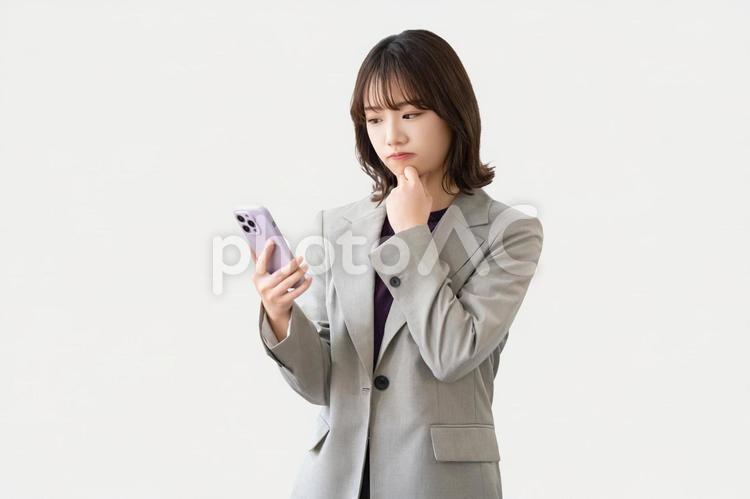スマホを見て考える女性・ビジネスウーマン 女性,困る,考えるの写真素材