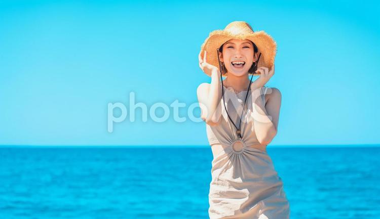 海で麦わら帽子を被る笑顔の女性 女性,夏,海の写真素材