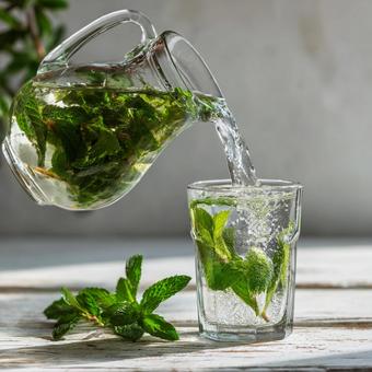 ミントの葉入り氷水がグラスに注がれる様子 ミントの葉入り氷水がグラスに注がれる様子の写真