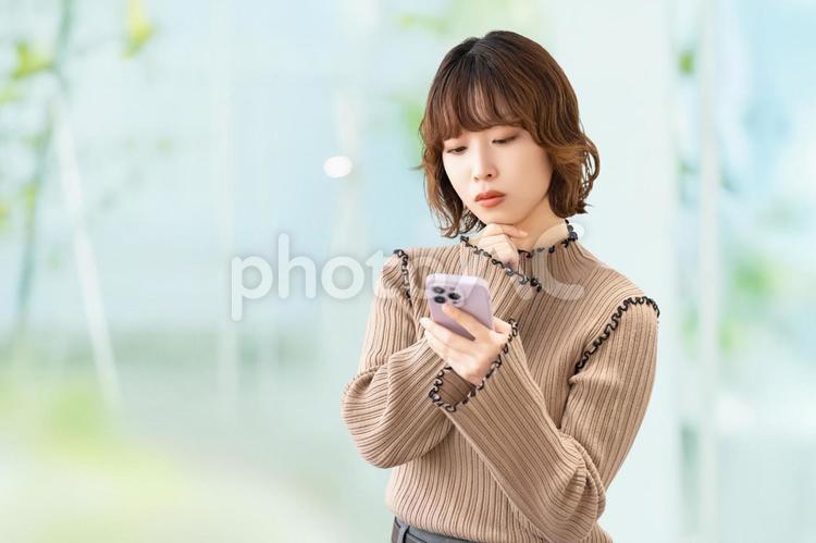 スマホを見て考える女性・ビジネスウーマン 女性,スマホ,困るの写真素材