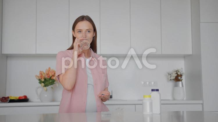 サプリメントを持って水を飲む女性 女性,人物,サプリメントの写真素材