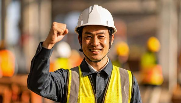 建設現場でガッツポーズする建設作業員の写真