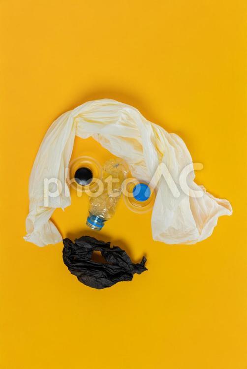 黄色の背景にビニール袋で髪の毛とペットボトルで鼻などを描いたキャラクター プラスチック,おもちゃ,顔の写真素材