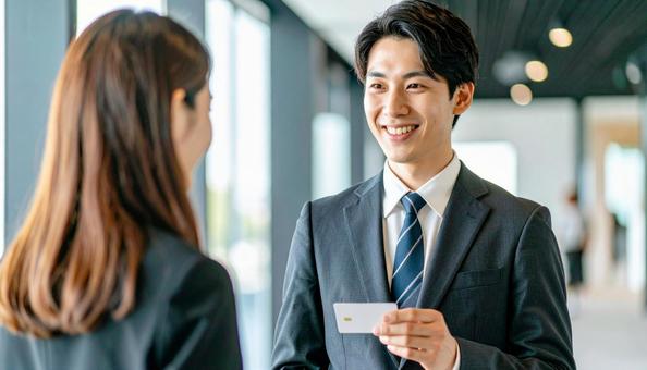 笑顔で名刺を差し出す男性社員の写真