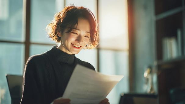 嬉しい通知を読む若手ビジネスパーソンの写真