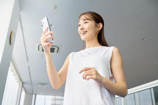 スポーツジムでスマホを操作する女性　美容 スマホ,女性,スポーツジムの写真素材
