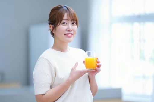手を添えてオレンジジュースを持つ女性 女性,笑顔,にっこりの写真素材