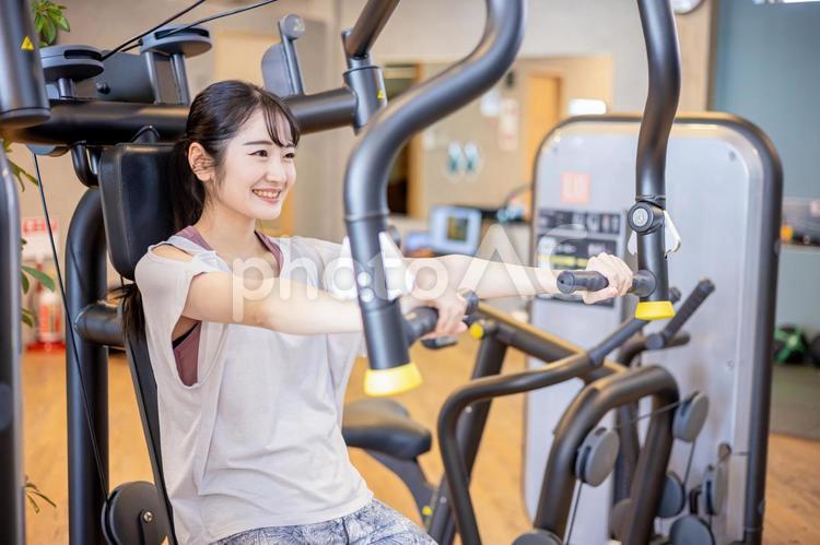 スポーツジムで体を鍛える女性（笑顔） 筋トレ,ワークアウト,チェストプレスの写真素材